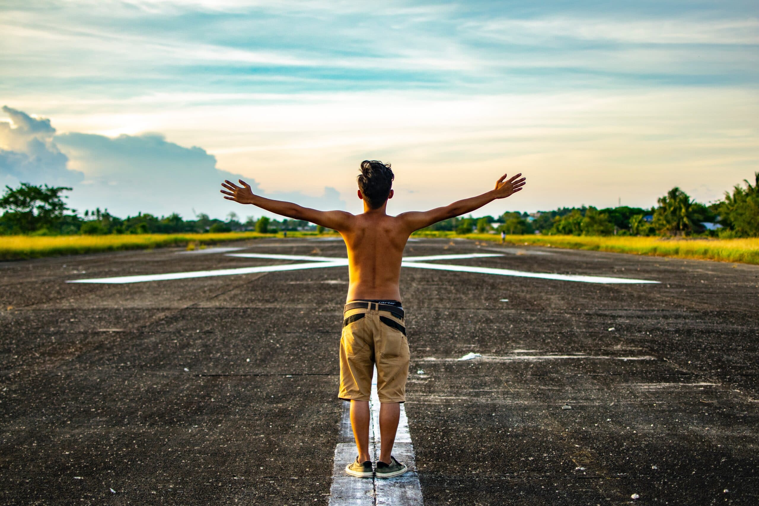 man raising hands standing on concrete road