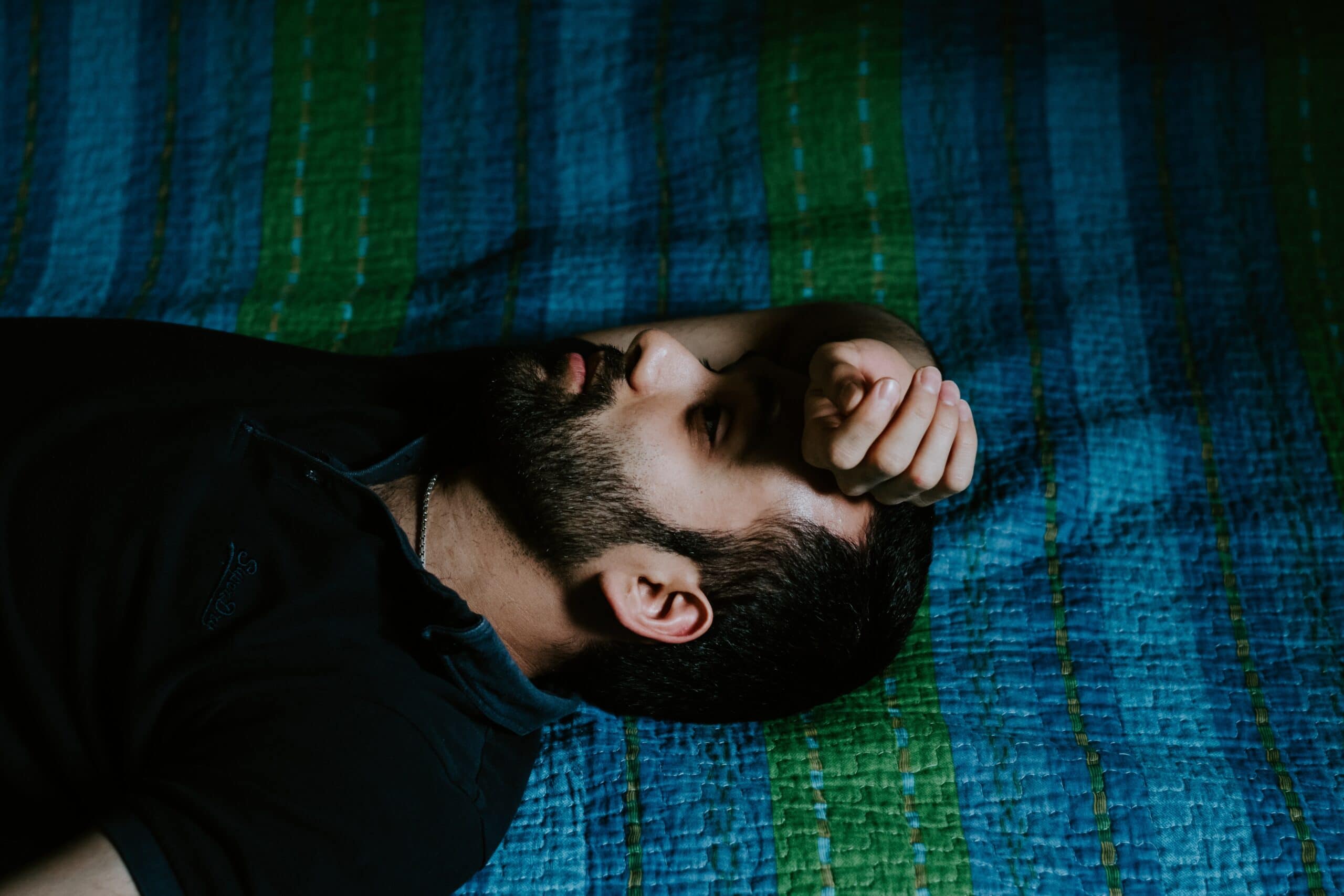 sanar man in black shirt lying on green textile