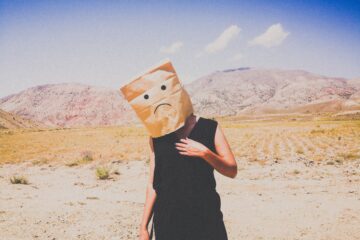 woman in black dress holding brown paper bag